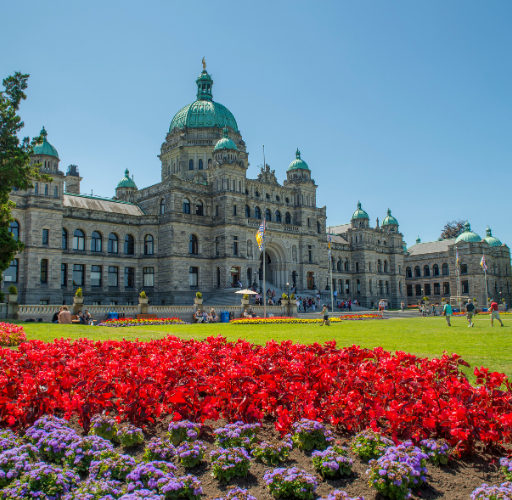 Visitors exploring Victoria BC's Inner Harbour with the Parliament Buildings and waterfront in the background